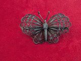 a butterfly brooch on a red surface