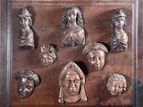 une plaque en bois sur laquelle figurent de nombreuses têtes différentes
