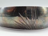 a silver bracelet that has a picture of a plant on it