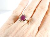 a woman ' s hand holding a ring with a ruby stone on it