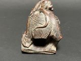 an old figurine of a man with a fish on his head