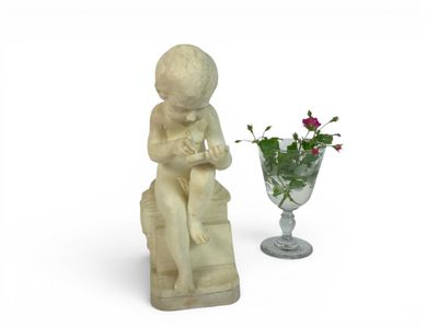 a statue of a boy sitting on a chair next to a vase of flowers