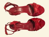 pair of red leather sandals with tassels on them on a white background