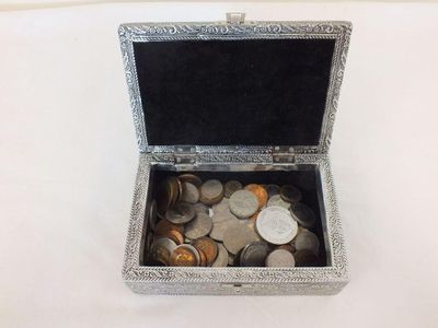 a small silver box filled with coins on a table