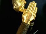 a gold statue of a person holding their hands up to their face