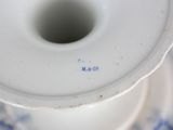 a close up of a white and blue vase on a table