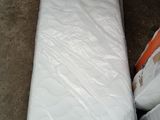 un matelas emballé dans du plastique, posé à même le sol