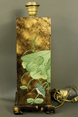 a lamp that is sitting on a stand with a flower on it