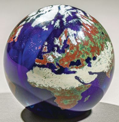 une boule de verre posée sur un socle, sur une surface blanche