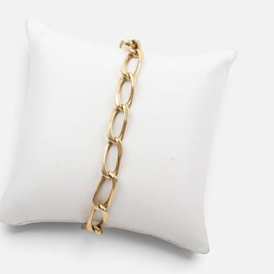 gros plan d'un bracelet en chaîne en or sur un oreiller