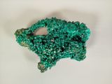 a close up of a piece of green crystals on a white surface