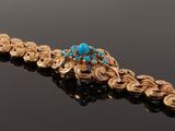 a close up of a gold bracelet with a turquoise stone