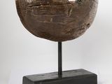 a wooden bowl on a stand on a white surface