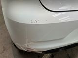 the rear end of a white car with a denting bumper
