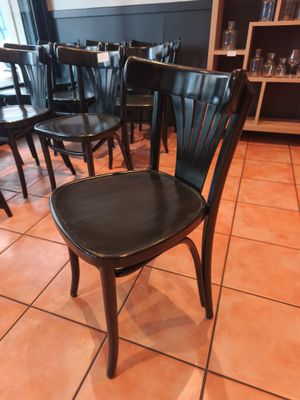 de nombreuses chaises noires dans un restaurant, avec une table en arrière-plan