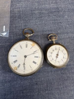 deux montres de poche anciennes posées l'une à côté de l'autre sur un tissu bleu
