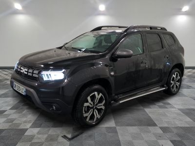 La Dacia noire est garée dans une grande pièce au sol carrelé en damier.