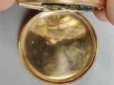 a person holding a gold pocket watch in their hand
