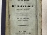 un vieux livre posé sur une table à côté d'un mur blanc