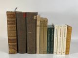 several old books are lined up in a row on a white surface