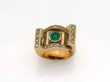 Gros plan sur une bague en or ornée d'une pierre verte