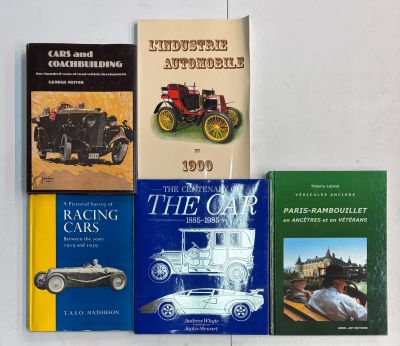 quatre livres posés sur une table blanche, avec une voiture au milieu