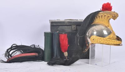 a helmet with a red feather on top of it next to a suitcase