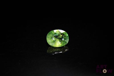an oval green tourmaline gems on a black surface