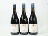 trois bouteilles de vin rouge sont posées sur une surface blanche