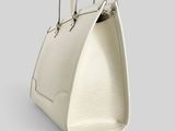 a white handbag on a grey background with a handle
