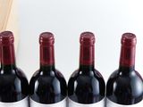 three bottles of red wine sitting on a table next to a bottle of wine
