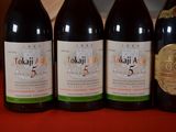four bottles of wine are lined up on a red table