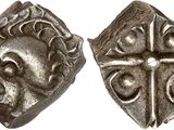 une pièce d'argent avec une croix au recto et un visage au verso