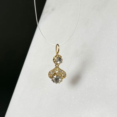 a close up of a necklace with a gold pendant on a white surface