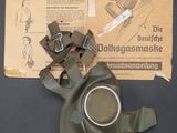 a gas mask on a table next to an open book