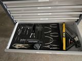 une boîte à outils posée par terre et contenant de nombreux outils