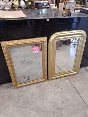 two gold framed mirrors on the counter of a store