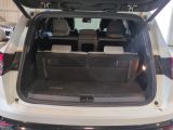 the back of a white car with its trunk open in a showroom
