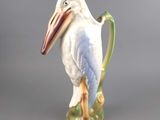 a figurine of a pelican sitting on a green handle