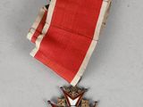 une image représentant une médaille ornée d'un ruban rouge et d'une étoile
