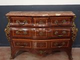 une commode en bois avec un plateau en marbre, posée sur un sol recouvert de moquette