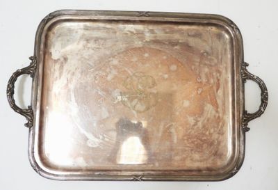 un plateau en argent muni de poignées posé sur une table blanche