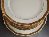 a set of four plates with gold rims on a gray surface