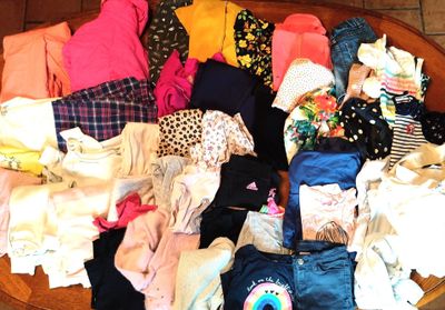 un saladier en bois rempli d'une multitude de vêtements, posé sur un sol carrelé