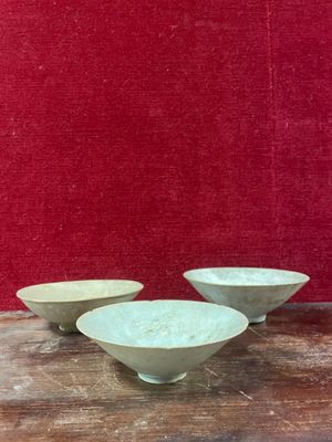 trois bols blancs posés sur une table en bois, près d'un mur rouge