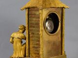 a gold clock with a man standing next to it