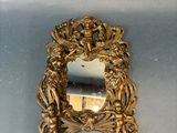 a gold mirror on the wall with a statue in it
