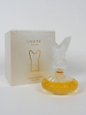 une photo d'un flacon de parfum posé à côté d'une boîte sur une table