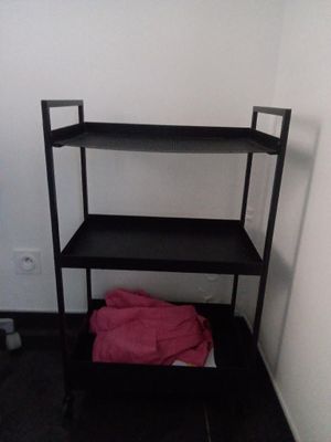 une étagère noire sur laquelle est posée une serviette rose
