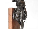 bronze statue of a woman with a bow on a wooden base